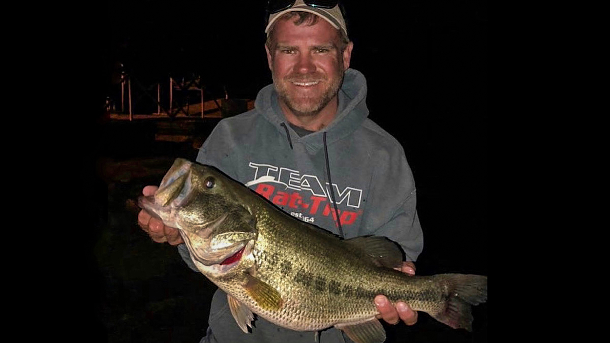 angler holding largemouth bass caught at night